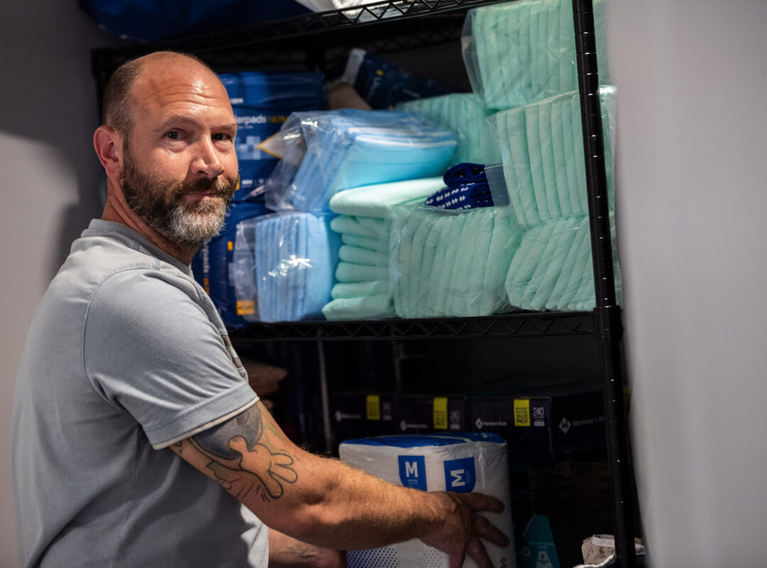 A man stocking a cupboard in Pappus House.