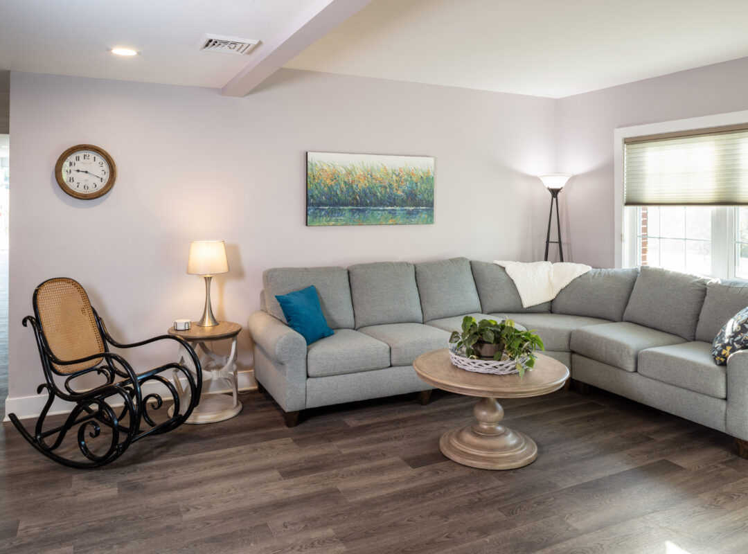 A sitting area inside Pappus House with a couch, table and rocking chair.