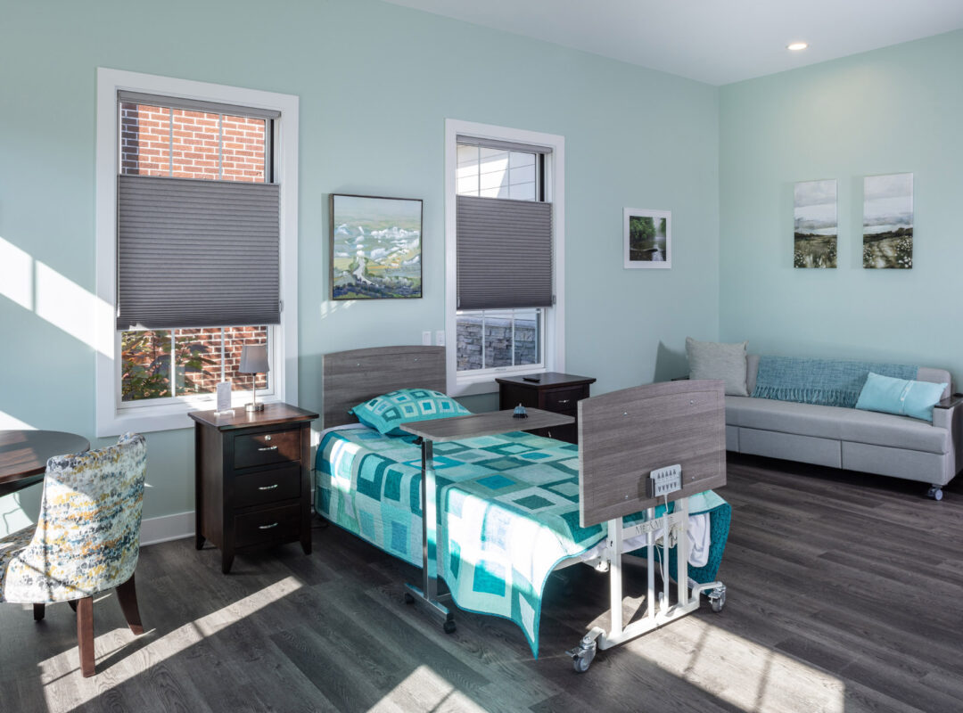 A green painted bedroom in Pappus House with a bed in the middle and a couch in the corner.