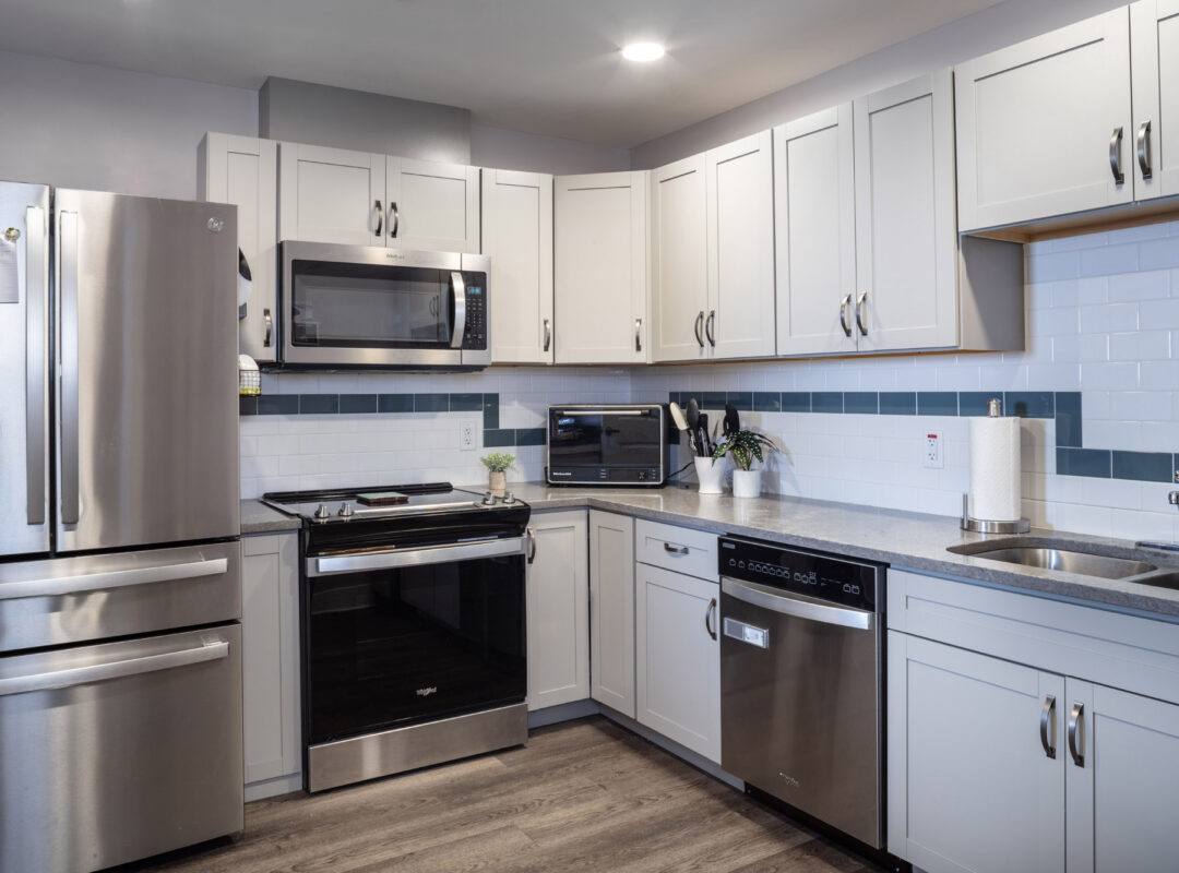 A clean kitchen with stainless steel appliances and wood grain flooring.